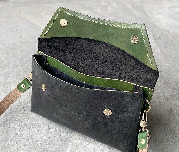 The black clutch bag open showing the hunters green detail