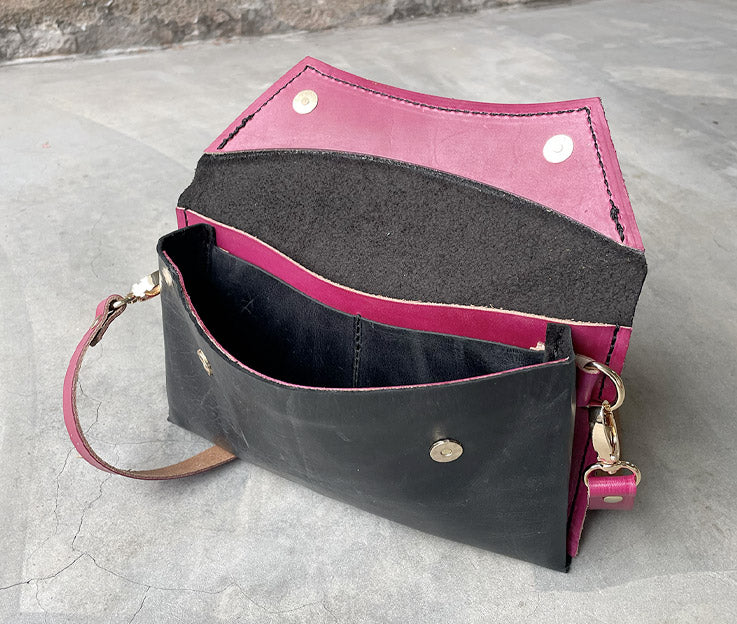 The black clutch bag open showing the rose pink detail