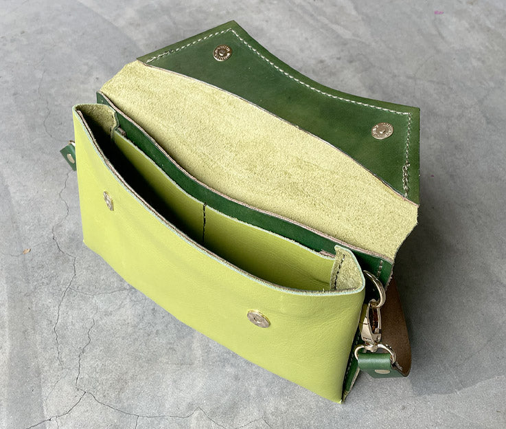 The lime green clutch bag open showing the hunters green detail