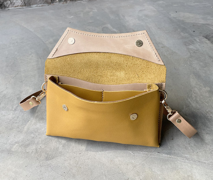 The ochre yellow clutch bag open showing the nude coloured detail