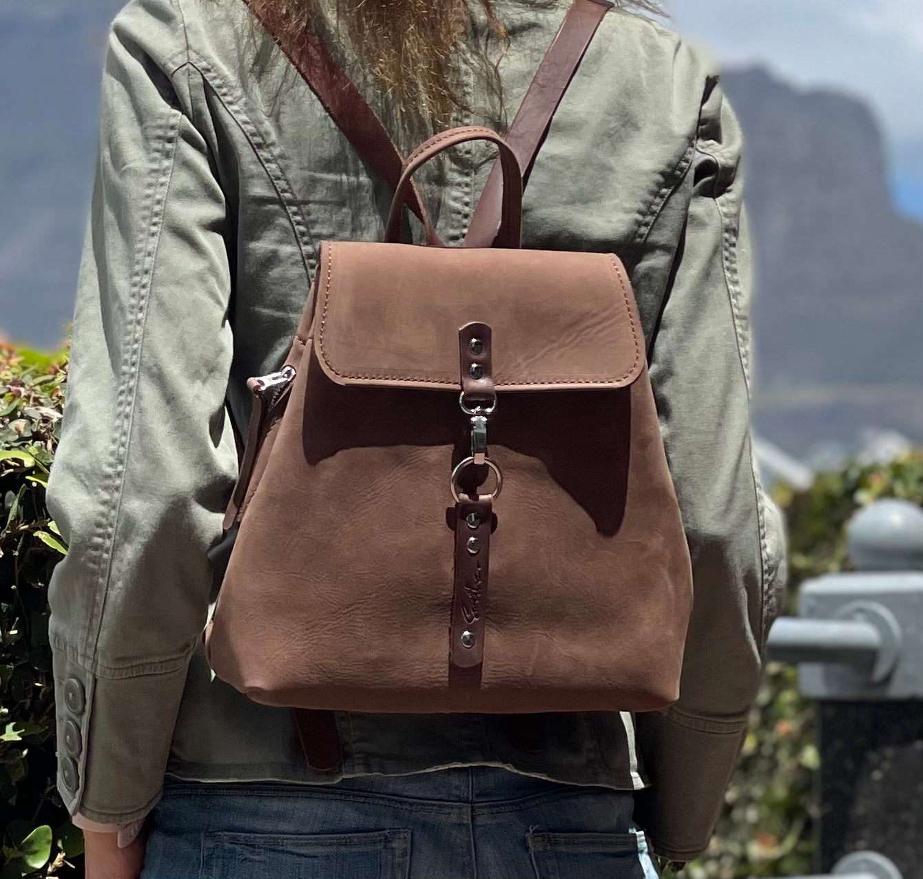 Model with Table Mountain in the backgroud displaying the brown leather backpack. This is a medium plus sized bag