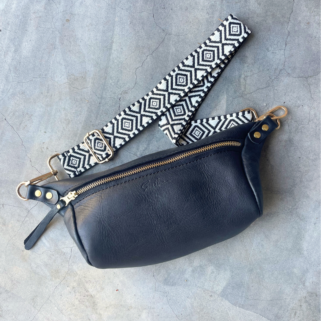 The black moon sling bag featured on a concrete screed surface.