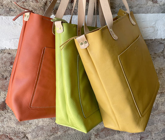 Sassy Shoppers steals the spotlight framed by a backdrop of rustic red brick. The vibrant leather bags in Coral, Lime & Ochre pops with personality, adding a bold touch to the urban-chic scene. #SmithcoSassy #UrbanStyle"